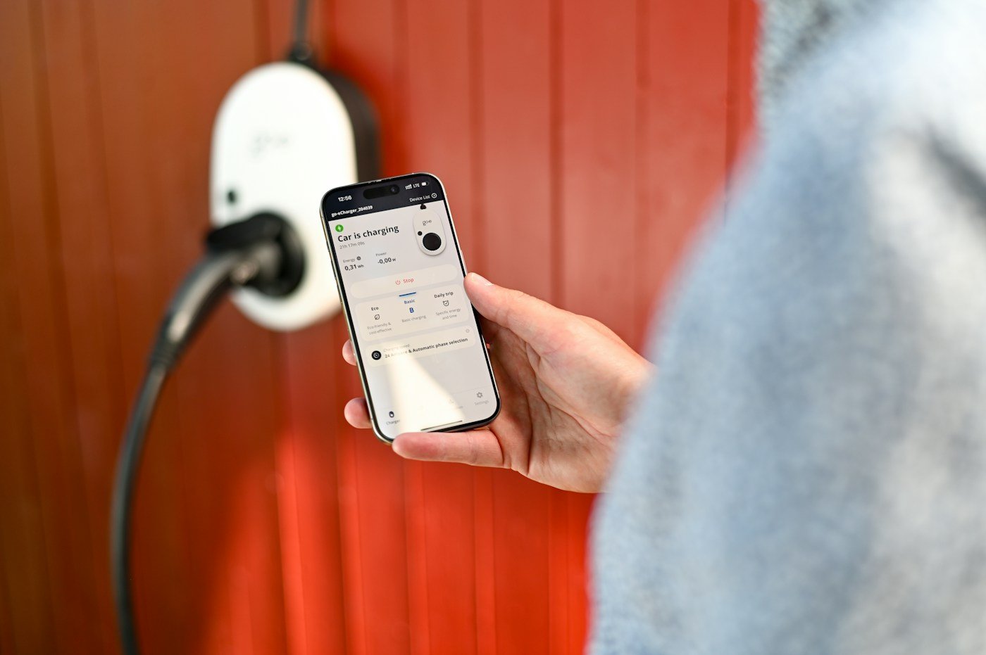 Smartphone app being used beside an electric vehicle charging point
