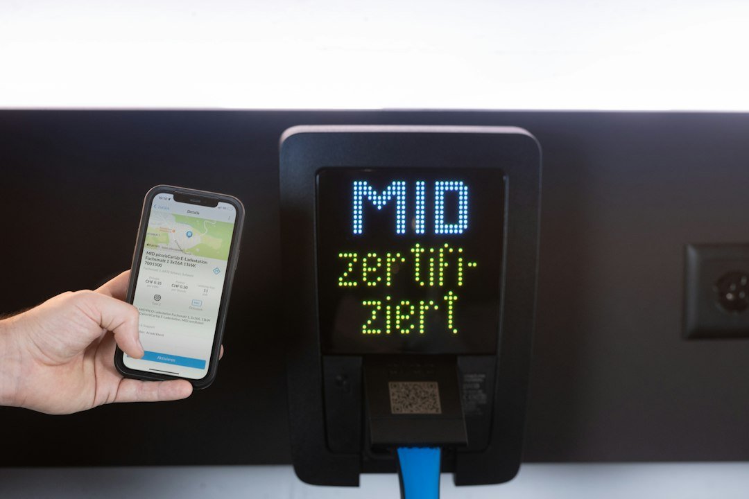 Smartphone beside an electric vehicle charging station, illustrating app-based charging support